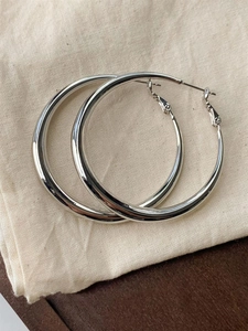 Close-up of polished silver hoop earrings on a textured linen background