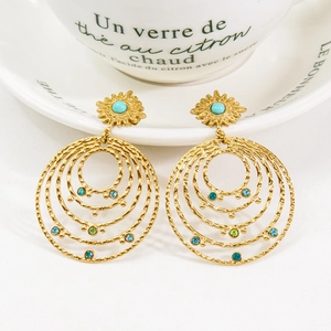 Detail of bohemian tiered gold earrings with colorful stones and turquoise center