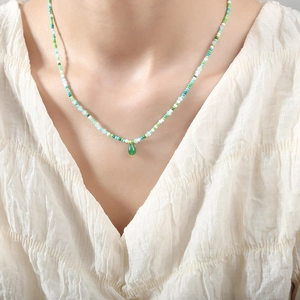Colorful beaded necklace with green gemstone teardrop pendant worn on a model