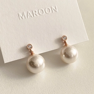 Macro view of rose gold pearl earrings with sparkling cubic zirconia on a card