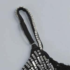 Macro detail of adjustable straps and silver rhinestones on a black sequin dress