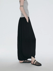 Detail view of the black wide-leg skirt pants with elegant drape and pleated texture
