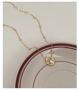 Detailed close-up of s925 silver gold-plated necklace with pearl U-shaped pendant