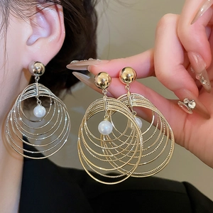 Detailed macro view of layered gold circular earrings with white faux pearl pendants