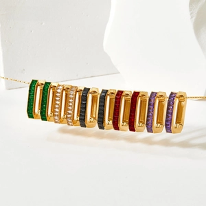 Detail of gold hoops featuring rectangular colorful zircons on a white stone base