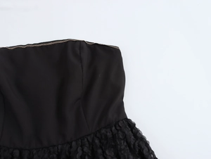 Detailansicht des trägerlosen Ausschnitts mit goldener Borte am schwarzen Kleid