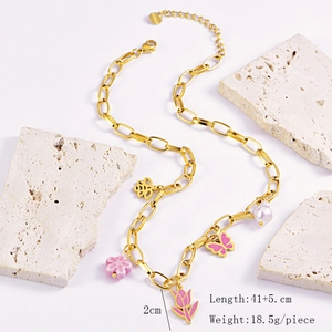 Detail of pink tulip and butterfly charms on a gold chain necklace with pearl accents