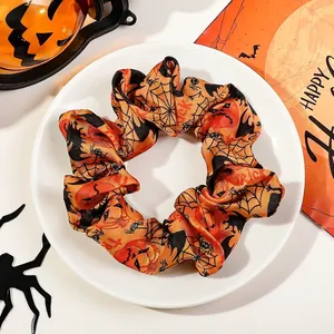 Detail view of Halloween scrunchie with pumpkin and spider web prints on a ceramic plate
