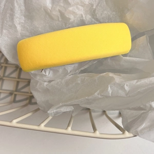Detail showing bright yellow fabric hair clip with twill texture in a white gift basket