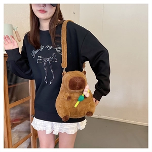 Close-up of a brown plush capybara crossbody bag worn by a model in casual setting