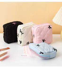 Detailed view of quilted makeup bags with embroidered bows in four pastel colors