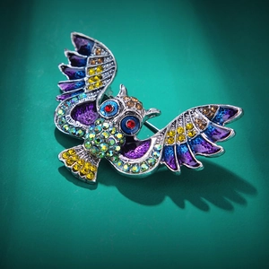 Vue rapprochée d'une broche hibou colorée avec strass et détails en émail