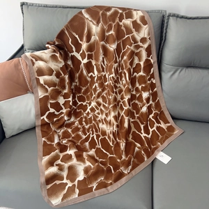 Detailed texture of brown and white giraffe print linen scarf folded on a sofa