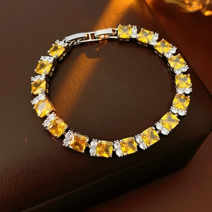 Primer plano macro de pulsera plateada con circonitas amarillas cuadradas sobre cuero