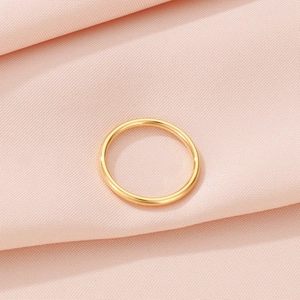 Detailed top view of a minimalist gold stainless steel ring on pink textured fabric background