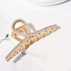 Detail of a gold hair claw clip adorned with shimmering pearls and sparkling rhinestones