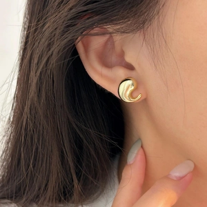 Close-up of minimalist golden teardrop stud earrings with a high-polished curved design