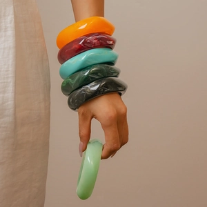 Close-up of thick geometric resin bangles in marble textures on a model wrist