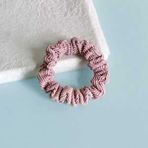 Gros plan d'un chouchou rose en velours côtelé avec texture sur un support blanc
