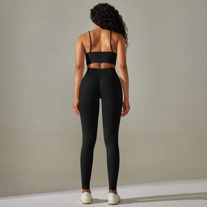 Detail view of seamless cross-strap sports bra and high-waisted leggings in black