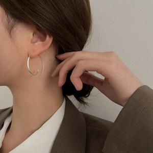 Close-up of minimalist silver irregular hoop earring worn by a model in a modern style