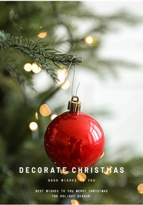 Close-up of a glossy red Christmas ornament with gold cap hanging on a green tree branch