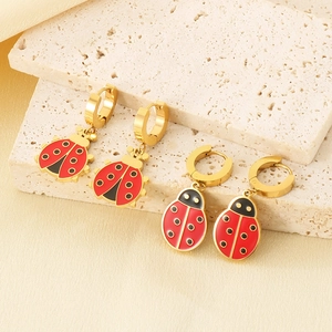 Macro detail of red and black enamel ladybug earrings on gold stainless steel base