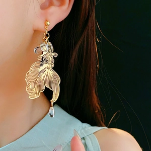 Detail of golden koi fish earrings with beads and water drop pendant on model