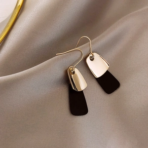 Minimalist gold metal hook earrings with black matte rectangle pendants on silk fabric