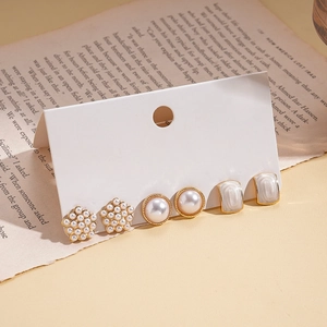 6-piece set of gold pearl and white enamel stud earrings on an elegant display card