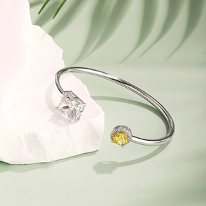Detail of silver bangle with square white stone and yellow zircon on stone pedestal