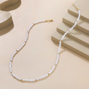 Baroque pearl necklace with irregular cream beads and gold accents on a display stand