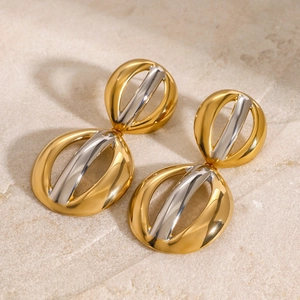 Macro shot of two-tone gold and silver oval earrings on a textured stone surface