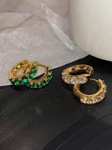 Detail of gold-plated brass hoop earrings with green and white cubic zirconia stones