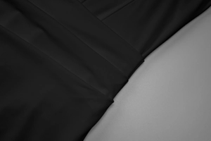Detailed macro view of the ruched black synthetic fabric on a bodycon party dress