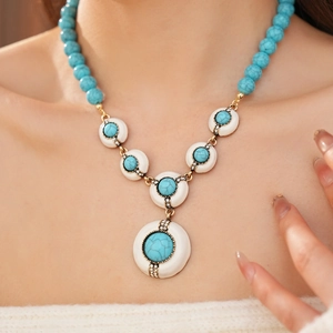 Detail of vintage gold necklace with blue stone pendant and turquoise beads on model