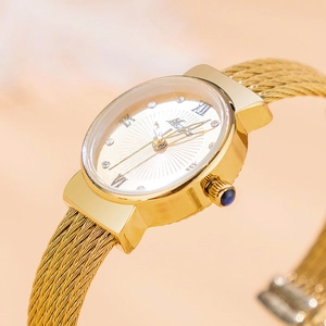 Macro shot of gold mesh watch band with diamond dial and blue gemstone crown detail
