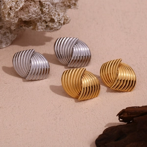 Macro detail of fan-shaped striped twisted metal earrings in gold and silver finish