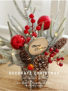 Close-up of mini Christmas tree with red berries, pine cones, and LED lights on wood base