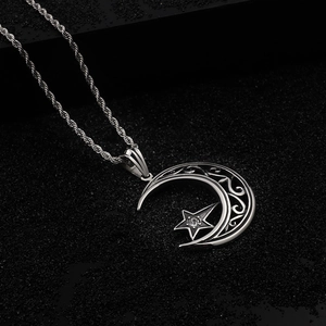 Détail d'un pendentif lune et étoile avec motifs filigranes et une pierre centrale sertie