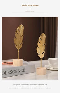 Detailed view of two golden metal ginkgo leaf sculptures on natural wooden bases