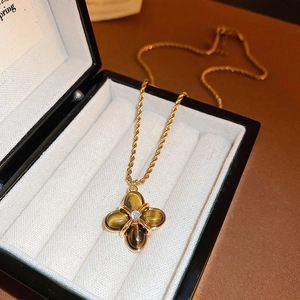 Detail of golden clover necklace with tiger eye stone and crystal in a jewelry box