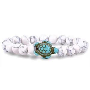 Dettaglio del bracciale con perline di pietra bianca e ciondolo tartaruga marina verde