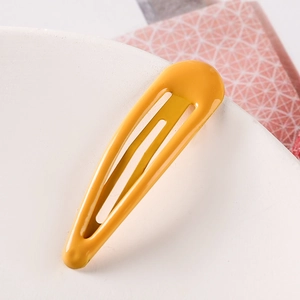 Close-up of a 5cm yellow candy-colored metal teardrop hair clip on a white tray