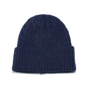 Close-up of deep blue cable knit beanie showing thick texture and folded cuff detail