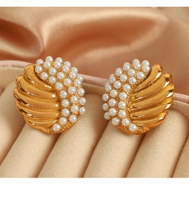 Detail of vintage gold-plated wing earrings with delicate white pearls in a jewelry box