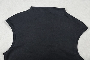 Detailed close-up of high neck stitching and premium black knit fabric on the dress