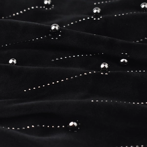 Detailed close-up of soft black chenille fabric with silver bead and stud wave patterns