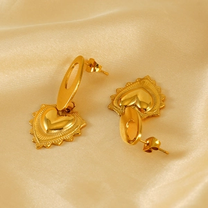 Boucles d'oreilles cœur dorées en acier titane sur un tissu de soie élégant