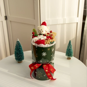 Bouquet di Natale con orsetto, rose rosse e fiori secchi in un secchiello verde